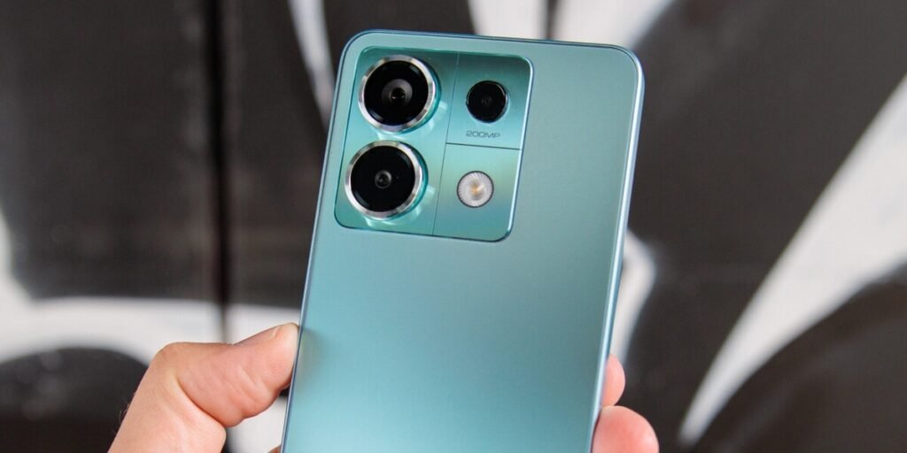Visão aproximada da parte traseira de um celular Xiaomi Redmi Note 13 Pro 5G, mostrando o módulo de câmera em um bloco retangular prateado. O texto "200MP" está visível. A cor do aparelho é um tom de azul-claro ou verde-água.HyperOS 2.2

